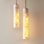 modern cylindrical marble pendant light with warm illumination, showcasing natural marble texture, hanging against a light-colored wall for elegant home decor