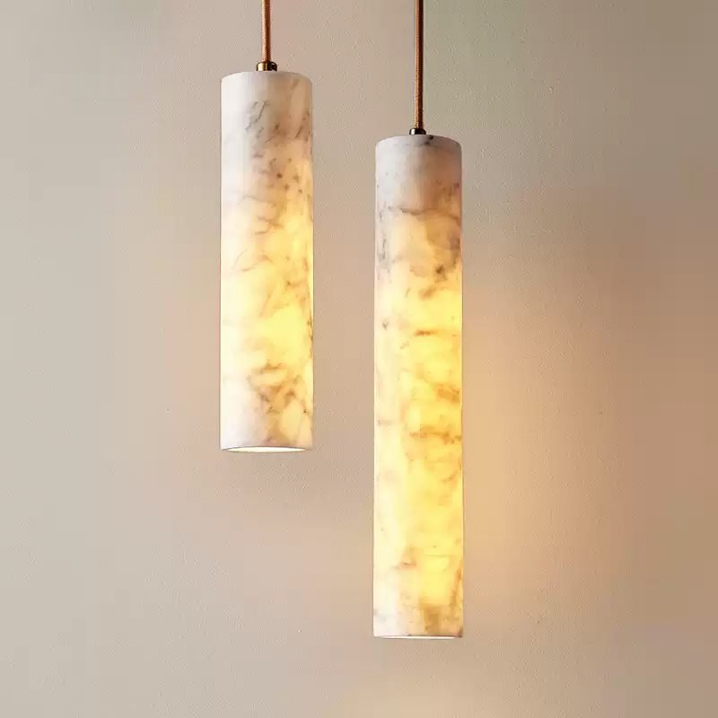 modern cylindrical marble pendant light with warm illumination, showcasing natural marble texture, hanging against a light-colored wall for elegant home decor
