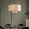 Modern Double-Layer Linen Drum Pendant Light hanging above a marble table with green plants and a black chair against a grey brick wall, ideal for living room and dining room decor