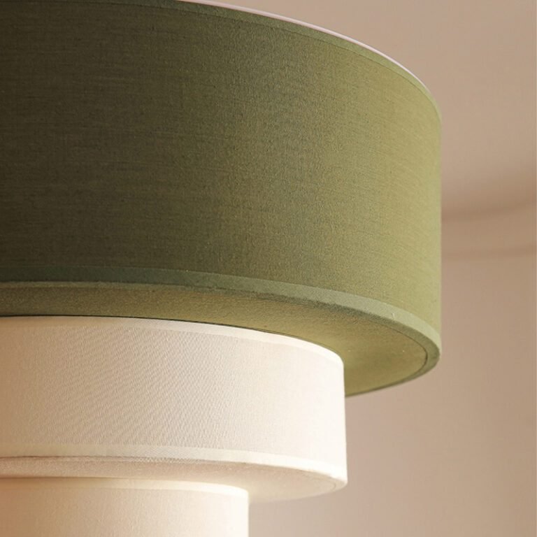 Retro modern multi-layer linen drum pendant light with green and beige fabric shades, hanging in a room with an arched window and abstract art, ideal for living room and dining room decor